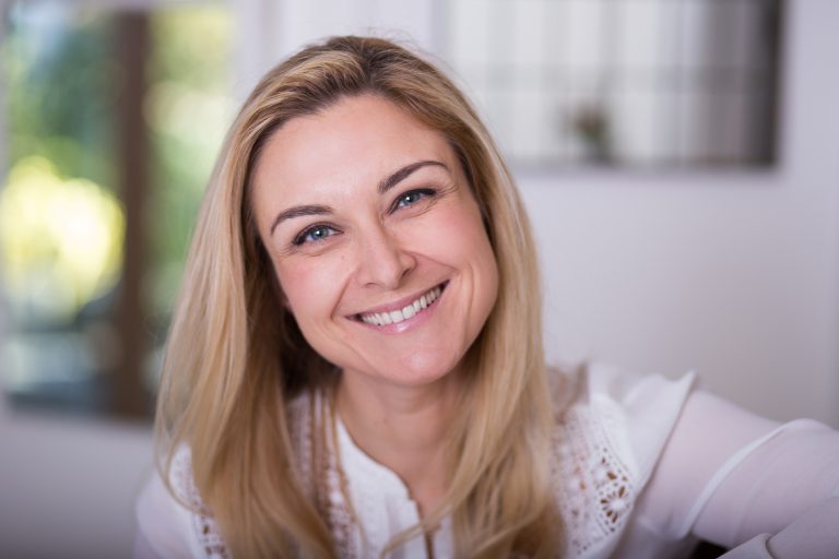 Smiling white woman with blonde hair in white shirt
