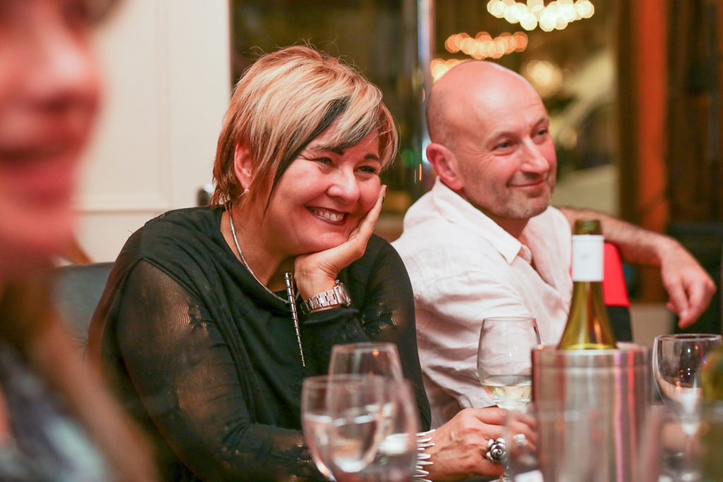 Woman sitting at table watching speech and laughing