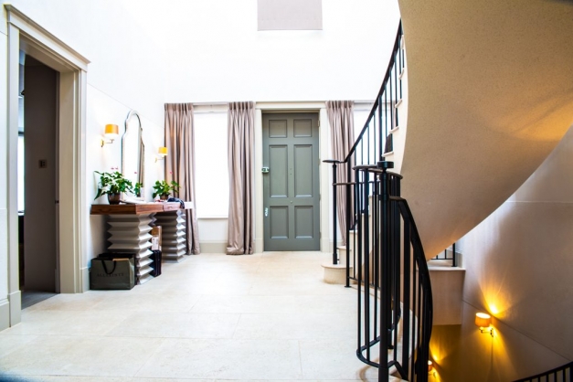 Hallway with big curved staircase and green front door