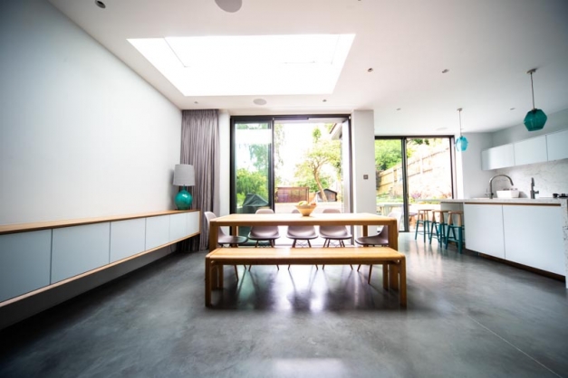Huge kitchen with concrete flooring and a dining table with pink chairs