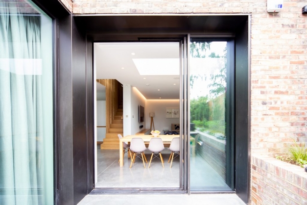 View from outside of kitchen through sliding glass doors with kitchen table and pink dining chairs
