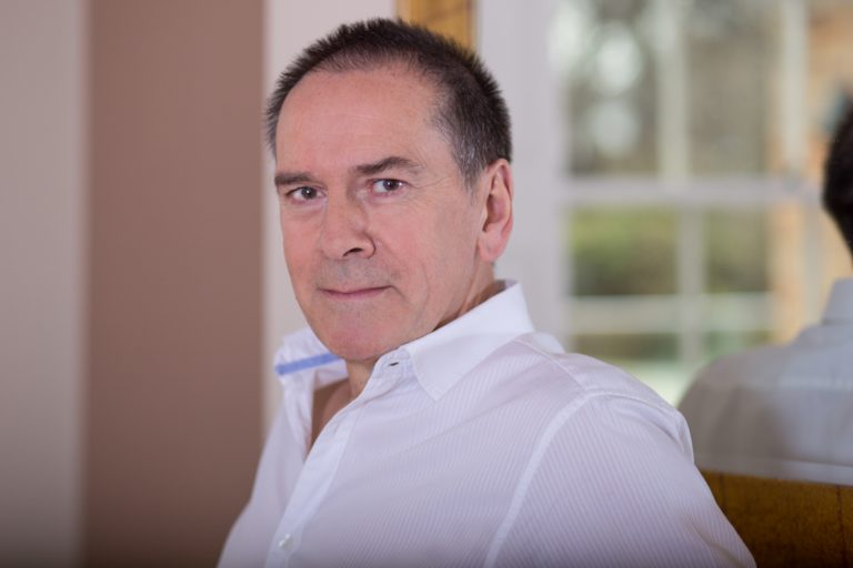 Man standing against a mirror in white shirt