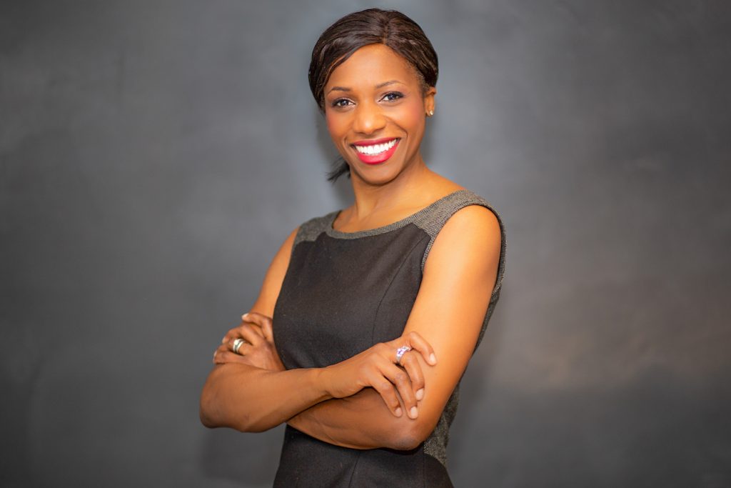 Black corporate woman in grey dress with big dazzling smile