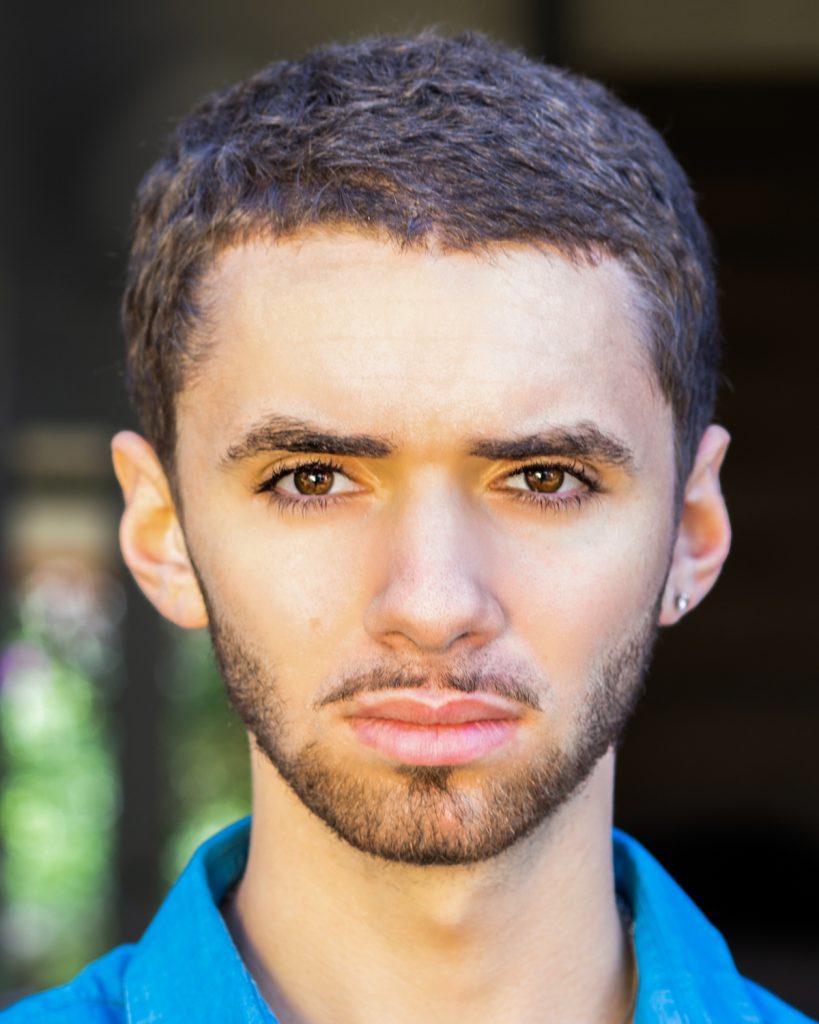 Young man with short dark hair and beard wearing a blue shirt