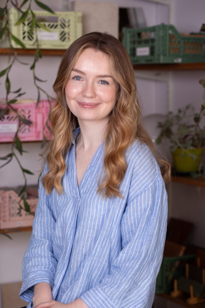 blonde woman in blue striped shirt smiling into camera