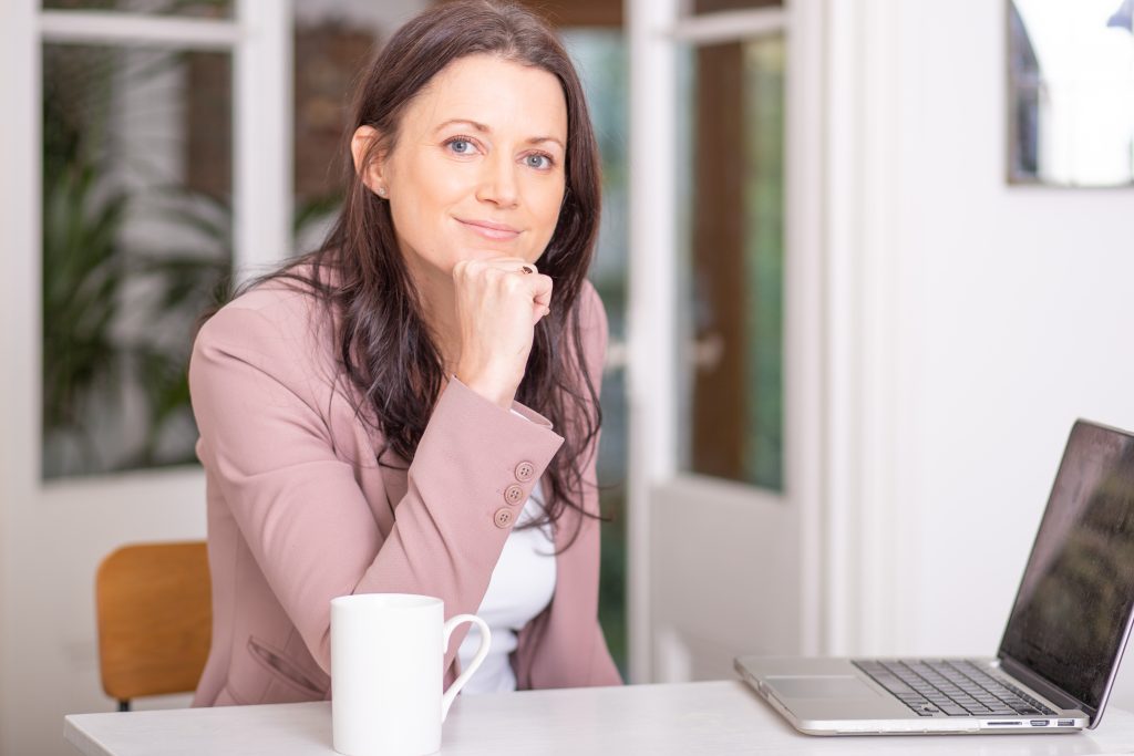 Business woman sitting at desk with laptop and cup of coffee