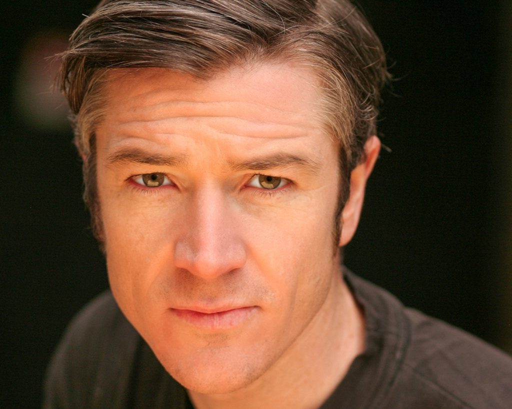 Dark haired actor staring into camera