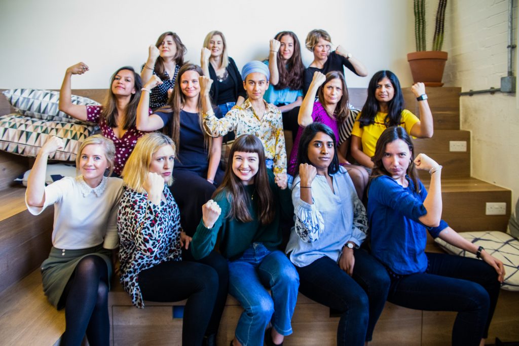 Group of women colleagues in an office holding up their arms