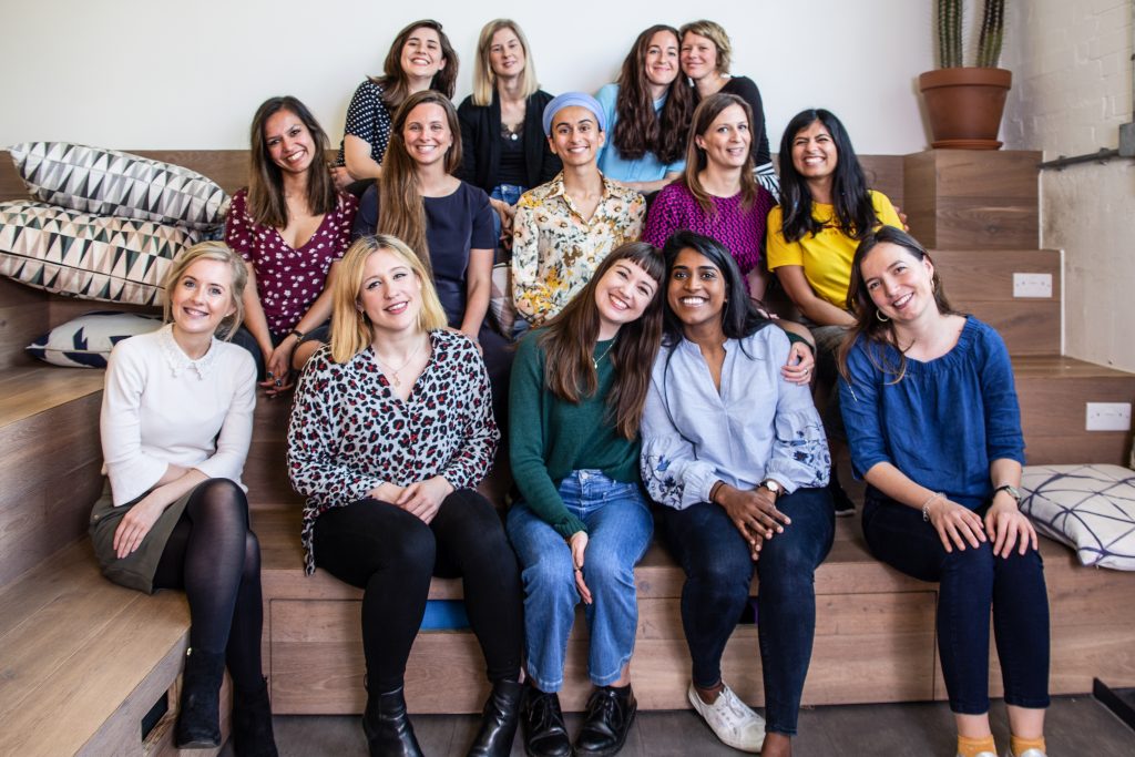 Big group of young women in an office sitting on benches