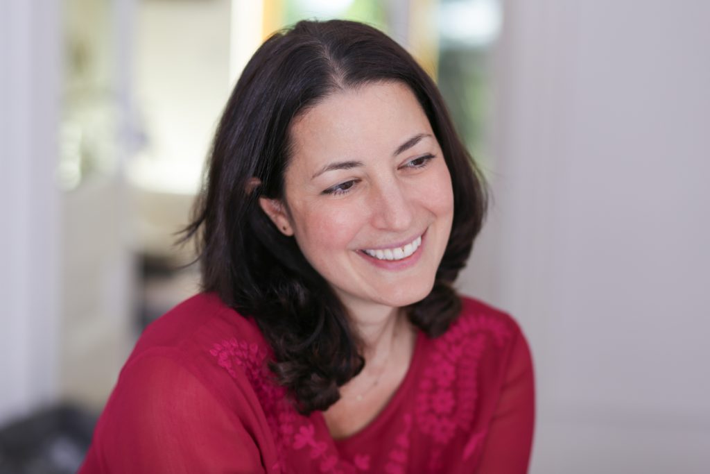 Happy picture of woman with dark hair and red top looking away from camera