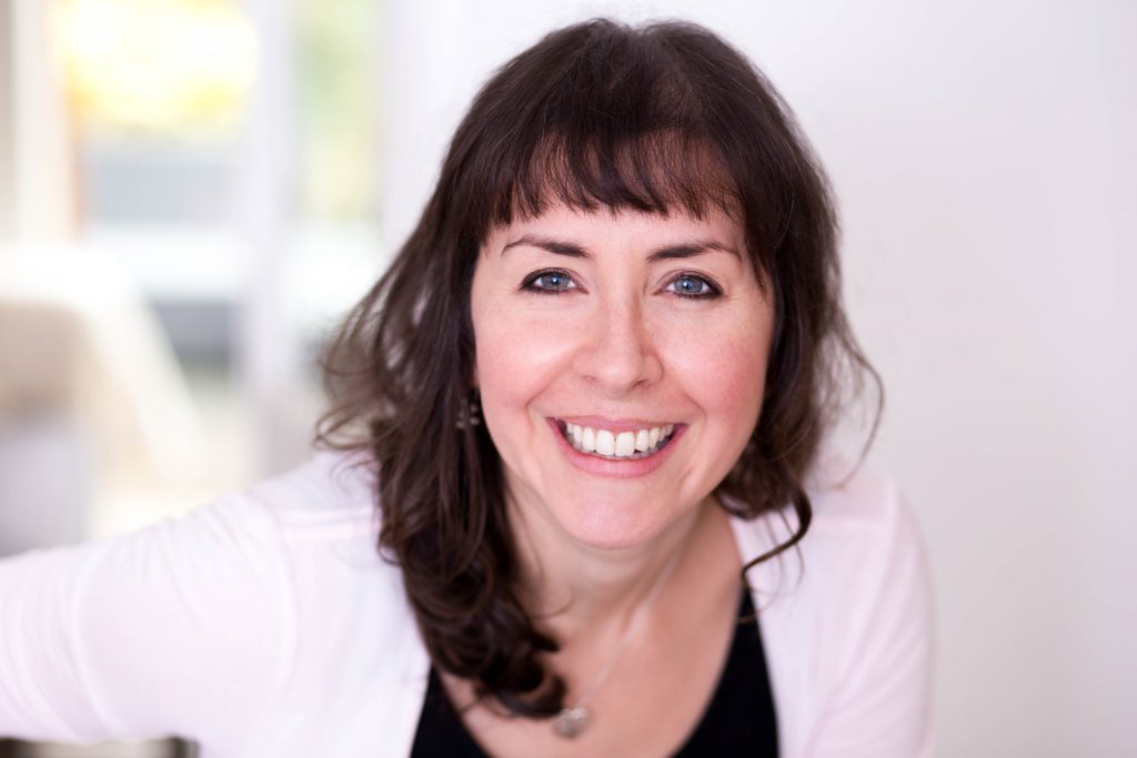 Smiley woman with dark hair leaning into the camera