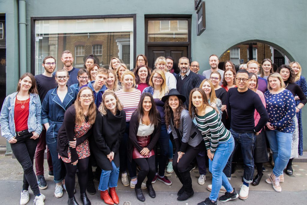 Big group of employees standing outside their office smiling